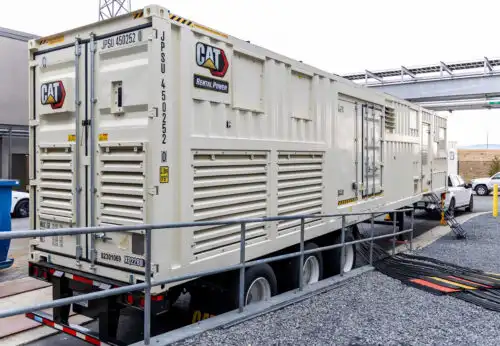 Large CAT industrial generator on a trailer at a loading area.